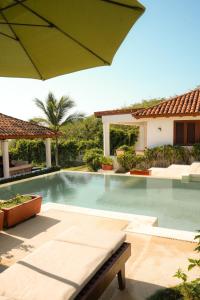 a swimming pool in a villa with an umbrella at Refugio de piedra - Troncones in Troncones