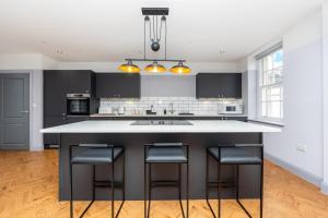 a kitchen with a large island with bar stools at Bath Street Penthouse in Bath