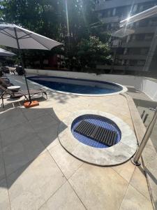 - une piscine avec un grill solaire à côté d'un parasol dans l'établissement APT Duplex 5min da praia - Circuito Carnaval, à Salvador