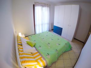 een slaapkamer met een bed met een groen dekbed bij Residence Pineta - Agenzia Cocal in Caorle
