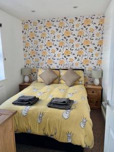 een slaapkamer met een geel bed met bloemenbehang bij The Royal Oak Cottages in Hunmanby