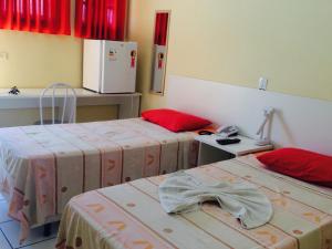 ein Zimmer mit zwei Betten und roten Kissen in der Unterkunft Capivari Centro Hotel in Capivari + 6 Fotos