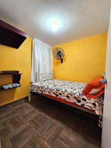 a bedroom with a bed with yellow walls and a fan at Sensity home Casa Flores, Hogareña y encantadora in Tehuacán