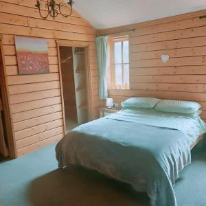 a bedroom with a bed in a wooden wall at Owl Cabin in Llanbrynmair