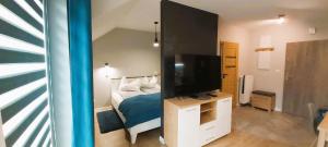 a bedroom with a bed and a flat screen tv at Apartament Turkusowy in Karpacz
