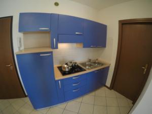 een keuken met blauwe kasten en een wastafel bij Residence Pineta - Agenzia Cocal in Caorle