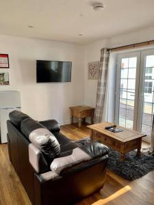 een woonkamer met een leren bank en een salontafel bij The Royal Oak Cottages in Hunmanby