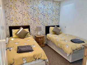 een slaapkamer met twee bedden en een nachtkastje bij The Royal Oak Cottages in Hunmanby