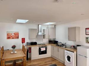 een keuken met witte kasten, een tafel en een fornuis bij The Royal Oak Cottages in Hunmanby