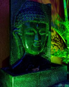 a green statue of a buddha sitting on a table at Morada de Rashid - Com Banheira de Imersão in Praia do Rosa