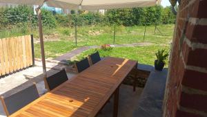a wooden table and chairs under an umbrella at l'escale familiale in Lachapelle-sous-Gerberoy