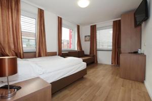 a hotel room with a bed and a couch and windows at Apartment Hotel am Sand in Hamburg