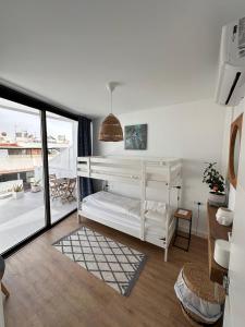 a bedroom with white bunk beds and a balcony at Papá Totë Deluxe in Playa Honda