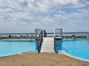 a boardwalk leading to a swimming pool on the beach at Studio Nina, accès plage et piscine in Cul de Sac