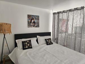 a bedroom with a white bed with two pillows at Studio Nina, accès plage et piscine in Cul de Sac +18 photos