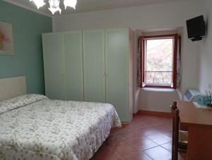 a bedroom with a bed and a desk and a window at La casetta di Anna in Villalago
