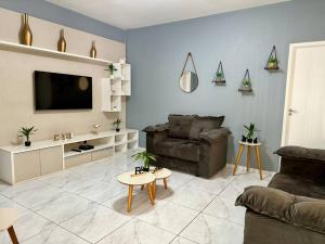 Casa na Vila No coração Gonzaga في سانتوس: غرفة معيشة مع أريكة وتلفزيون بشاشة مسطحة