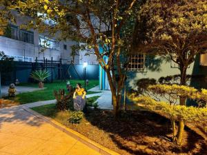 Casa na Vila No coração Gonzaga في سانتوس: امرأة تقف بجانب شجرة على الرصيف