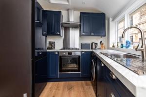 a kitchen with blue cabinets and a stove at Charming Cottage - Country Views in Bath