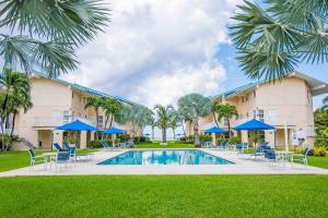 a resort pool with chairs and blue umbrellas at Enjoy Sunsets at Fully Equipped Condo at the Beach in George Town