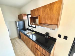 a small kitchen with a sink and a refrigerator at Chic 2BR Condo, Private Jacuzzi and 2 Free Bikes in Tulum