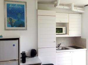 a white kitchen with a sink and a microwave at Studio Indigo Pierre et Vacances in Sainte-Anne +8 photos