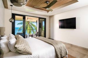 ポトレロにあるBeachfront Pool 5 BD Villaの白いベッドと薄型テレビのある寝室