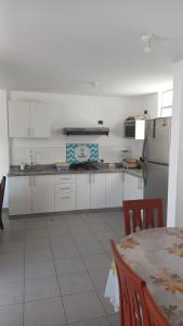 a white kitchen with a table and a refrigerator at Departamentos Cerro Azul P2 in Cerro Azul