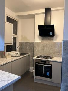 een keuken met een fornuis en een spoelbak bij Oxborne Rooms UK - Plaistow in Londen