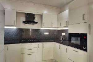 a white kitchen with white cabinets and black appliances at 2 Bedroom River view apartment in Aluva, near Cochin Airport in Alwaye +11 photos