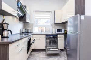 a kitchen with white cabinets and a stainless steel refrigerator at Rheinland Apartments - Stilvolle, moderne Unterkunft mit kostenfreiem WLAN und Parkplatz in Andernach