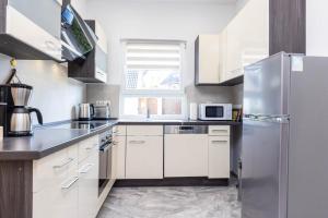 a kitchen with white cabinets and a stainless steel refrigerator at Rheinland Apartments - Stilvolle, moderne Unterkunft mit kostenfreiem WLAN und Parkplatz in Andernach +13 photos
