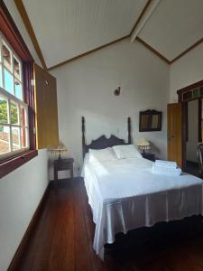 a bedroom with a white bed in a room at Pousada Padre Toledo in Tiradentes