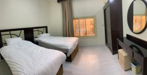 ein Hotelzimmer mit zwei Betten und einem Spiegel in der Unterkunft فيلا ريام السيف in Al Namas