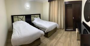 ein Hotelzimmer mit zwei Betten und einem Fernseher in der Unterkunft فيلا ريام السيف in Al Namas