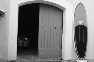 a door with a surfboard leaning against a building at Le Petit Molière Chambres d'hôtes et gîte in Servian