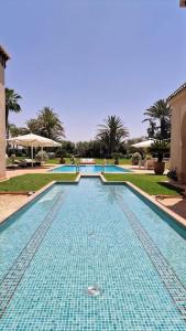 a swimming pool with blue tiles in a resort at Villa Alcázar Marrakech in Had Abdallah Rhiat
