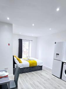 a white bedroom with a bed and a refrigerator at The Wembley Park Apartment in London