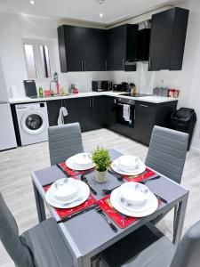 a kitchen with a table and chairs and a kitchen with black cabinets at The Wembley Park Apartment in London