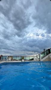 a large blue swimming pool with a cloudy sky at Loft Prainha 101, arraial do cabo in Arraial do Cabo +11 photos