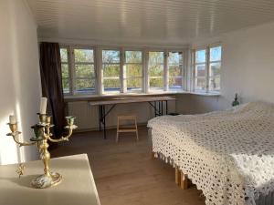 a bedroom with a bed and a table and windows at Særpræget & teatralsk villa, med skøn udsigt in Borre
