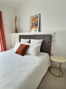 Un dormitorio con una cama blanca con almohadas y una mesa en Le Baule D'air, en La Baule