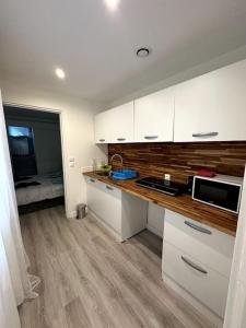 a kitchen with white cabinets and a wooden counter top at Drancy, spacieux hébergement in Drancy +6 photos