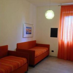 una sala de estar con 2 sofás naranjas y una ventana en Stay Like Home Milano, en Corsico