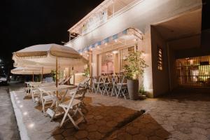 グァラトゥバにあるSol e Mar Pousada Surf Barの建物の外に傘を配したテーブルと椅子