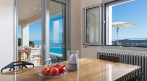 a dining room with a table with a bowl of fruit on it at Elounda Luxury Villas in Elounda