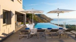 a patio with tables and umbrellas and a swimming pool at Elounda Luxury Villas in Elounda