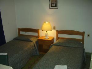 two beds in a hotel room with a lamp on a night stand at Edificio Sagasti in Piriápolis