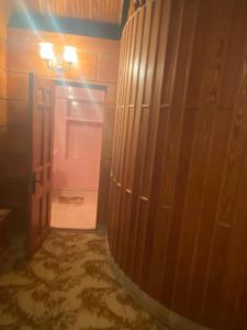 a bathroom with a wooden door and a hallway with a light at Gogol House in Kutaisi