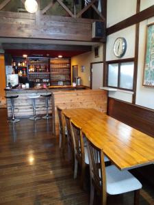 a dining room with a wooden table and a bar at Santana Lodge Hakuba in Hakuba